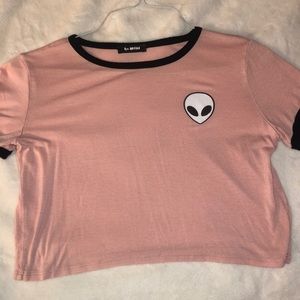 Baby pink cropped shirt with an alien logo.